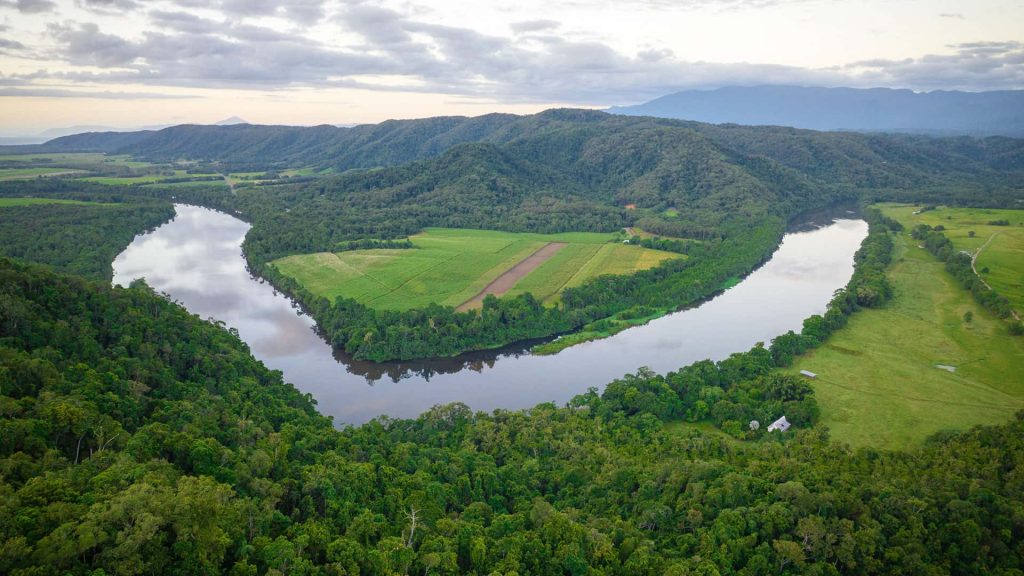 Drone view of a bend in the Daintree River, near to Wawu Dimbi, showing intact rainforest and farmland.